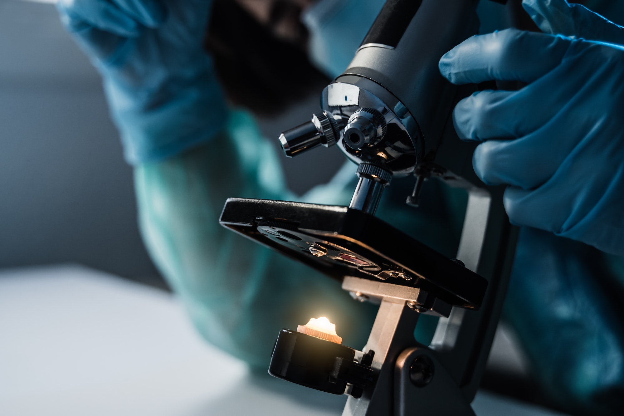 Medical doctor doing coronavirus research working with microscope inside hospital lab
